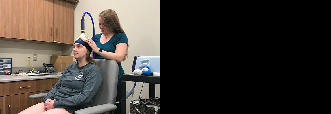 Appalachian alumna Amelia Bruce ’19, standing, prepares a study participant in order to measure the effect of brain stimulation on treating ankle injuries. Photo submitted