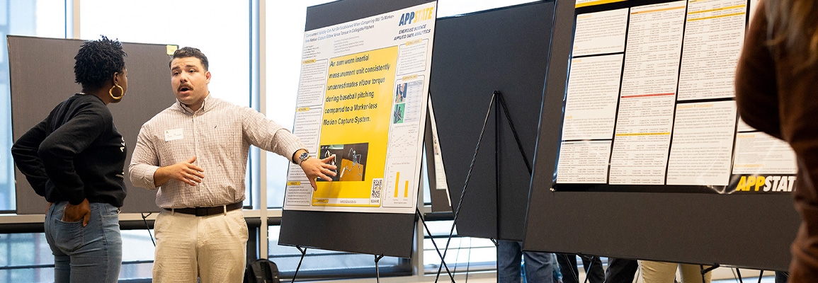 A student explains his research to a person.